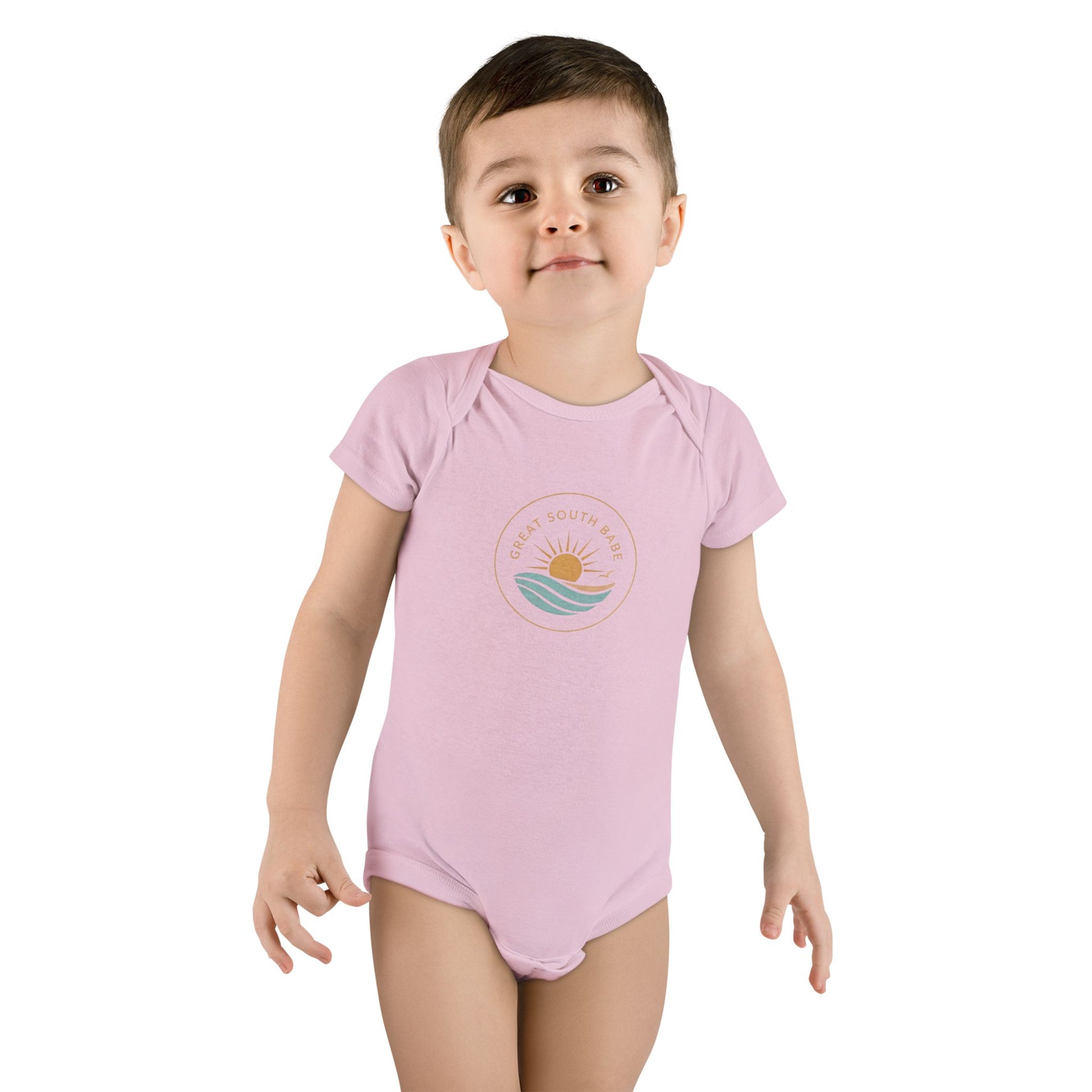 Toddler boy wearing light pink Great South Babe onesie with sun and waves logo